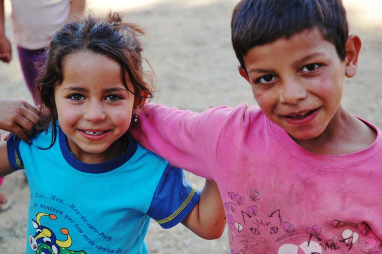 Two Roma children smiling with their arms around each other